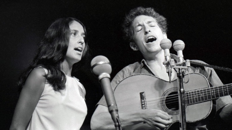 Black-and-white photo showing Joan Baez performing on stage with Bob Dylan in 1963