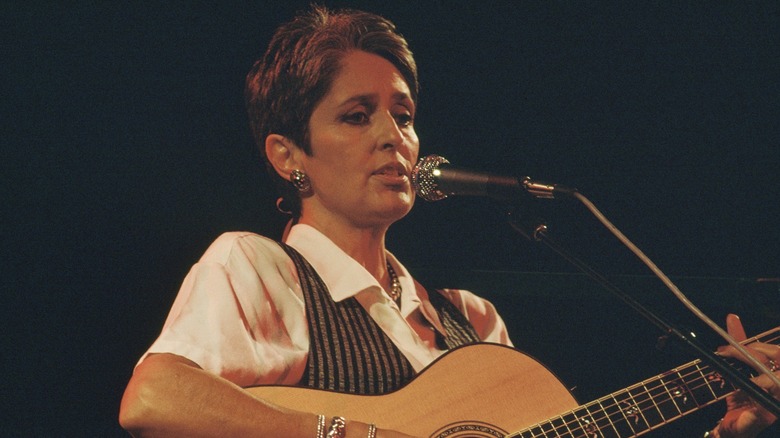 Joan Baez playing a guitar on stage in 1990