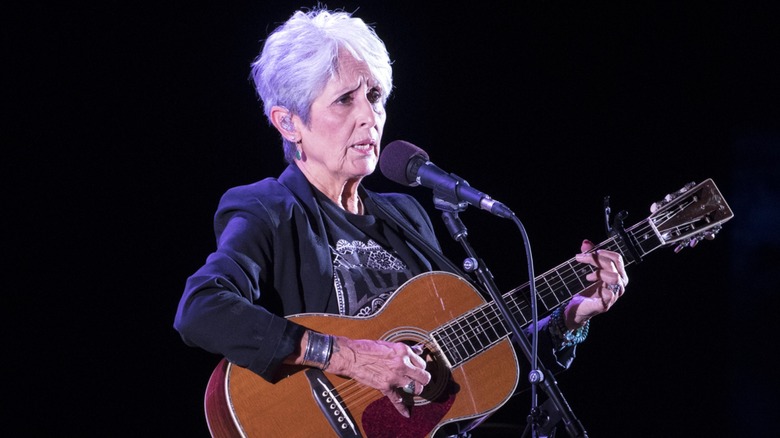 Joan Baez performing on stage with a guitar in 2018