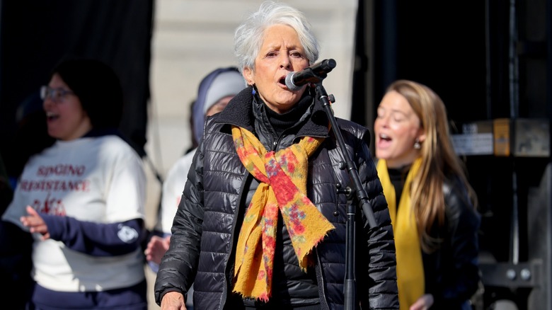 Joan Baez speaking into a microphone as part of a No Kings Rally in 2026