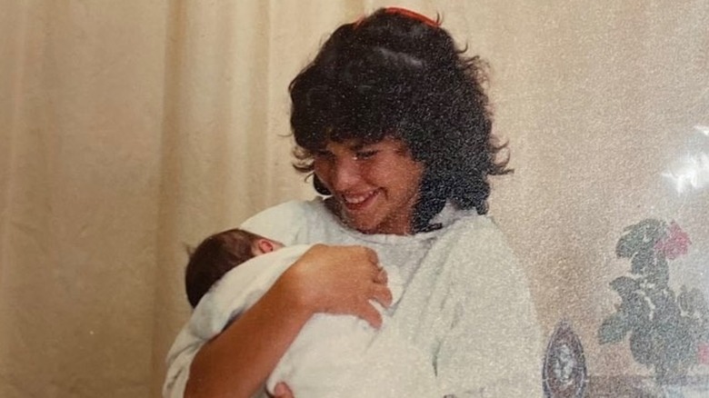 A young Lauren Sánchez Bezos smiling and holding her baby sister
