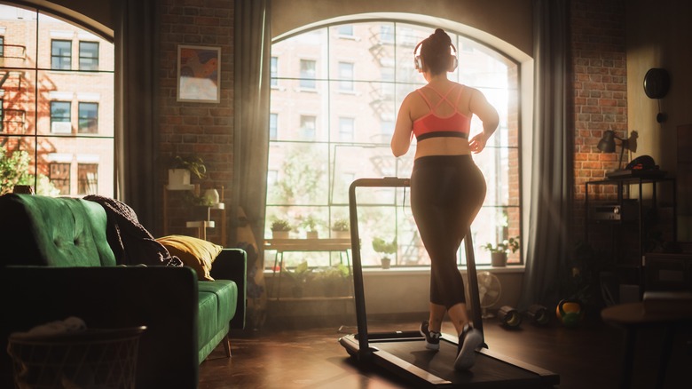 Woman runs on treadmill at home