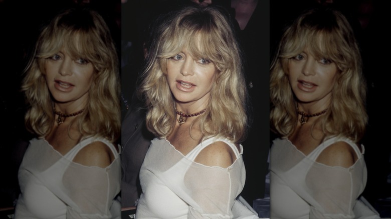 Goldie Hawn wearing a sheer white off the shoulder top with blond hair and bangs