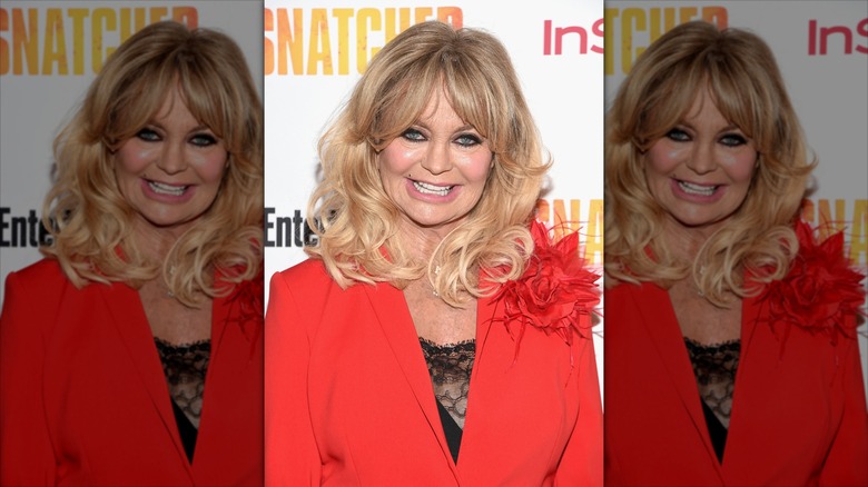 Goldie Hawn smiles wearing a red blazer