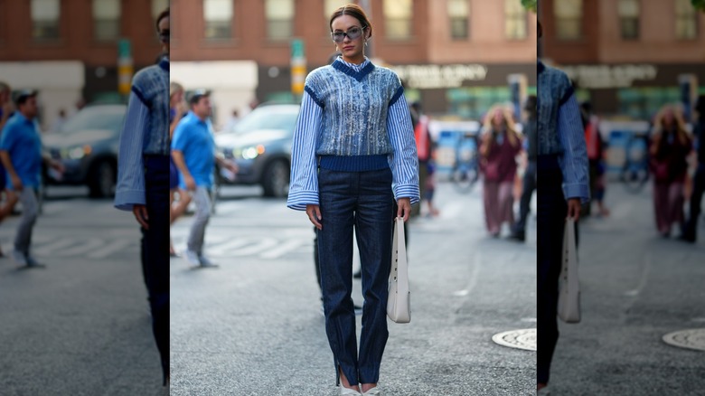Woman wearing a sweater vest and dark blue jeans