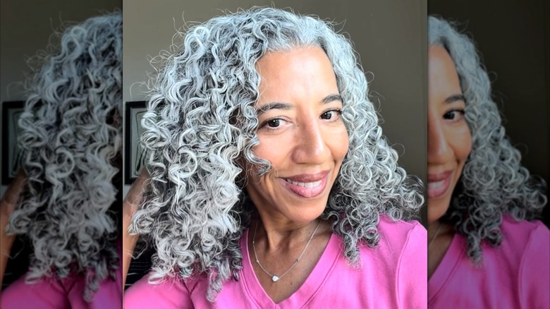 A woman smiling while showing her gray, cropped curly hair
