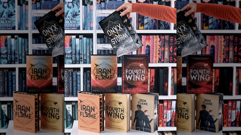 Pyramid of books from the "Fourth Wing" series, with an arm balancing "Onyx Storm" on top