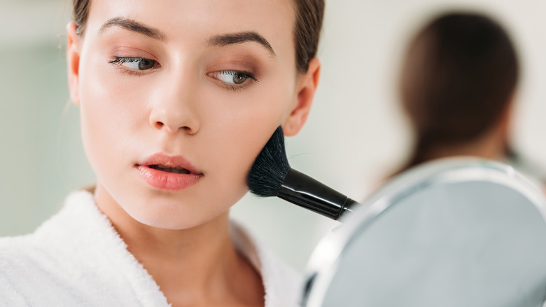 Young woman applying makeup 