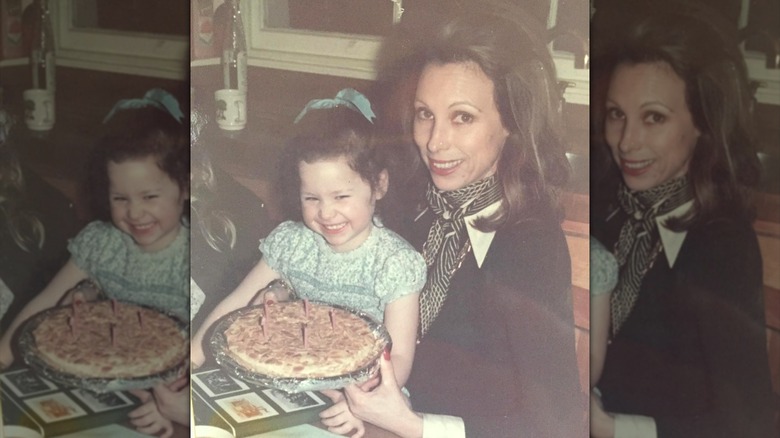 Young Minnie Driver holding a birthday cake alongside her mom