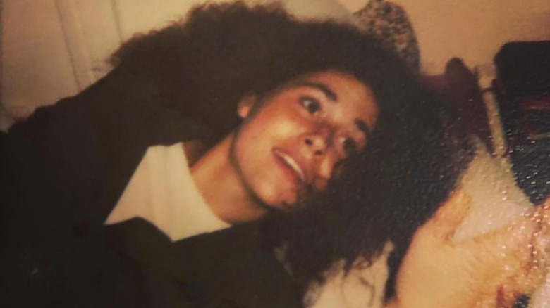Teenage Minnie Driver laying on a bed with voluminous hair