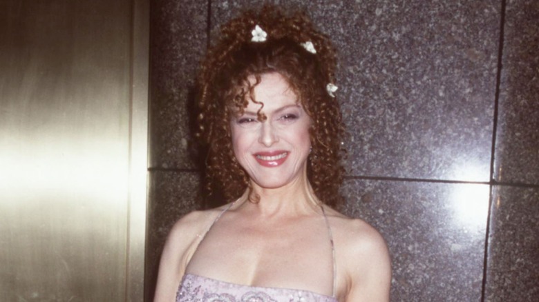 Bernadette Peters smiling with her hair styled half up with flower clips at an event in 2000.
