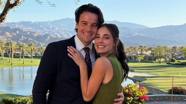 Kristen Vaganos smiling while hugging and posing with her boyfriend Nick Cafero in front of a mountaneous backdrop