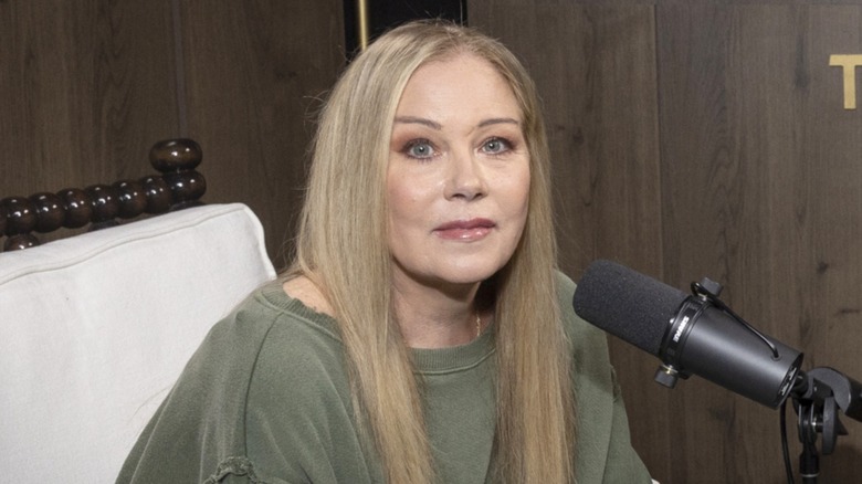 Christina Applegate posing with a neutral expression behind a microphone in 2024