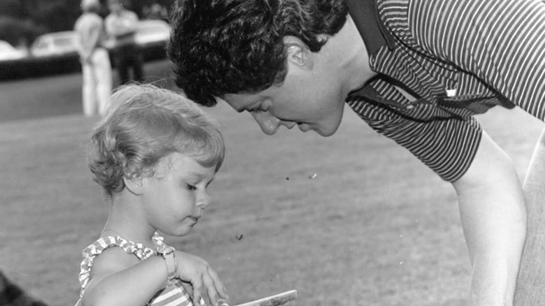 Black-and-white photo of a very young Chelsea Clinton with her dad Bill Clinton