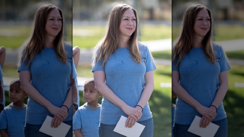 Chelsea Clinton smiling outdoors wearing a blue t-shirt