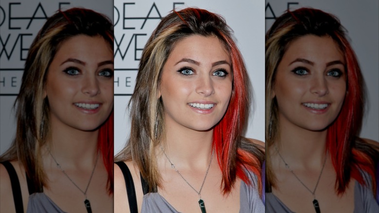 Paris Jackson smiling at a 2015 event with red streaks in her hair