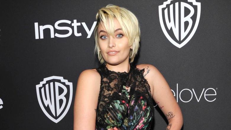 Paris Jackson posing on the red carpet with short hair in front of a black background in 2017
