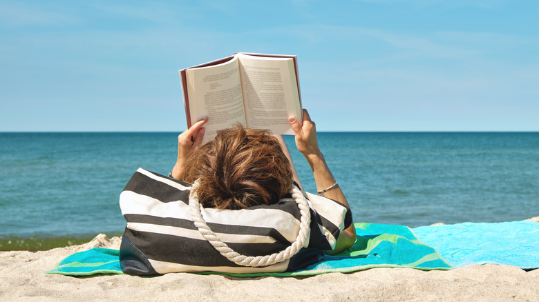 woman reading book on beach