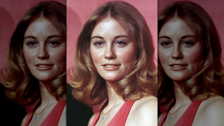 Cybill Shepherd posing on the red carpet in a red dress in front of a pink background in 1974