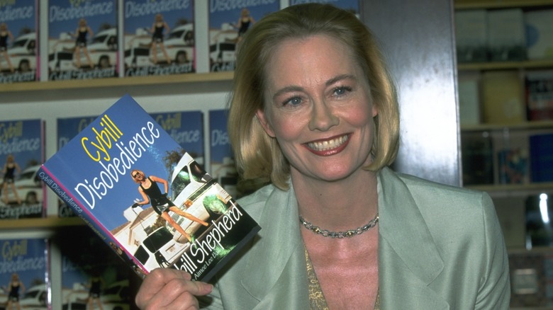 Cybill Shepherd smiling and holding a copy of her memoir in 2020
