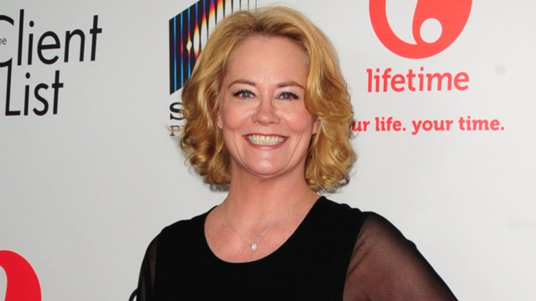 Cybill Shepherd posing on a red carpet in a black dress in front of a white background in 2012