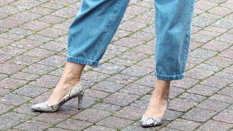 A woman in snakeskin print shoes and loose denim