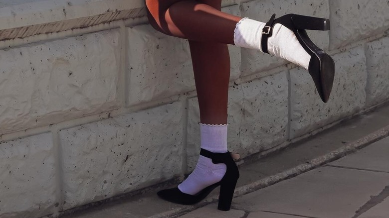 A woman wearing socks with heels with a buckle