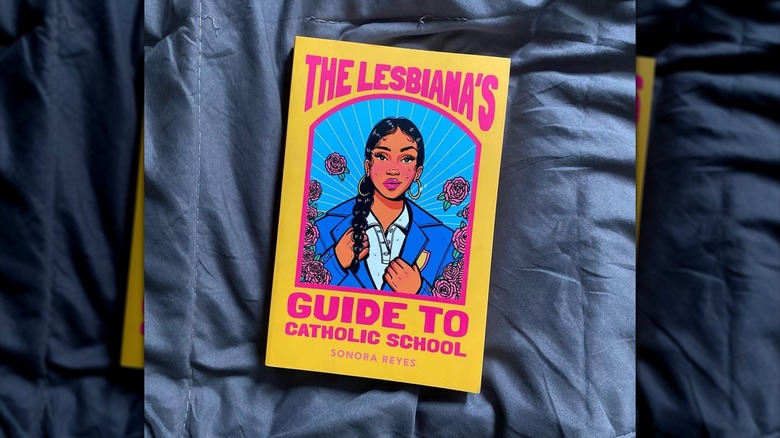 A copy of "The Lesbiana's Guide to Catholic School" laying on a blue sheet
