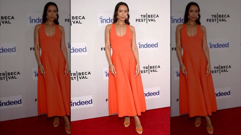Woman wears tangerine orange dress on red carpet