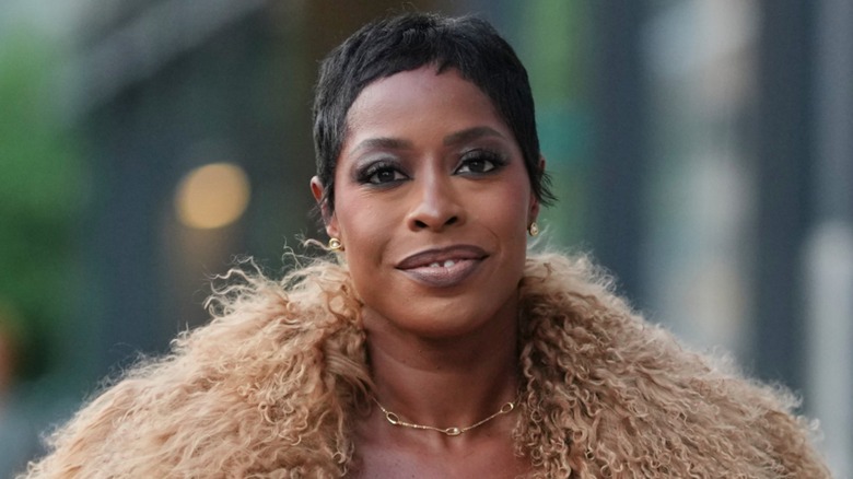 A woman walking the streets with a choppy pixie cut and faux fur jacket
