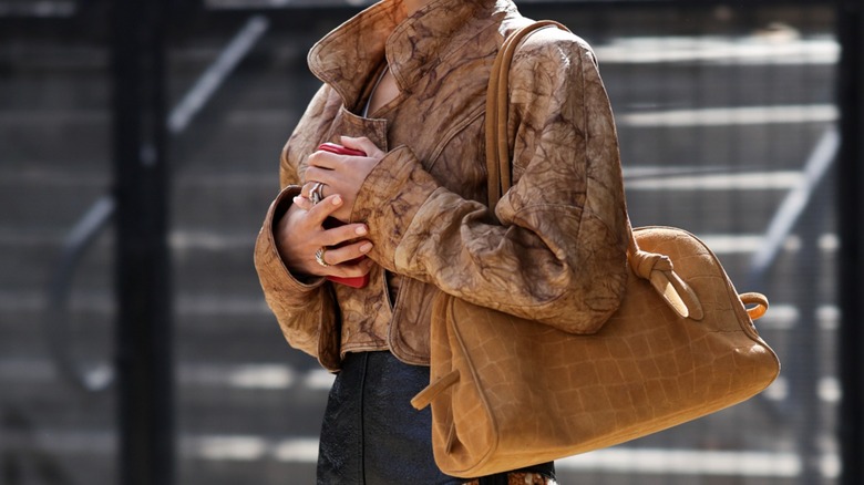 A woman carrying a yellow crocodile print bag