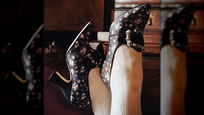 A person wearing dark floral print regency style shoes