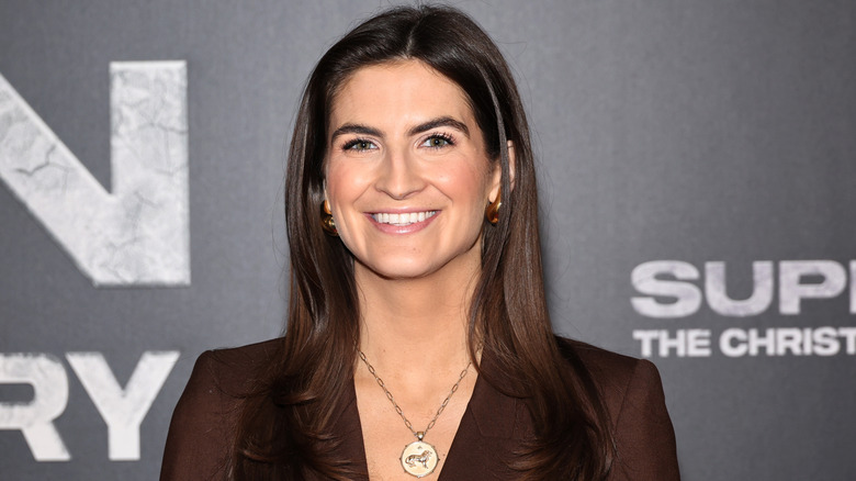 Kaitlan Collins smiling at the premiere of "Super/Man: The Christopher Reeve Story" while wearing a brown paintsuit
