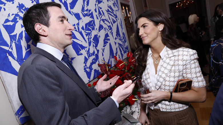 Kaitlan Collins speaking with Andrew Ross Sorkin at the Puck & The French Embassy's First Amendment Gala with her plaid jacket and brown slacks visible