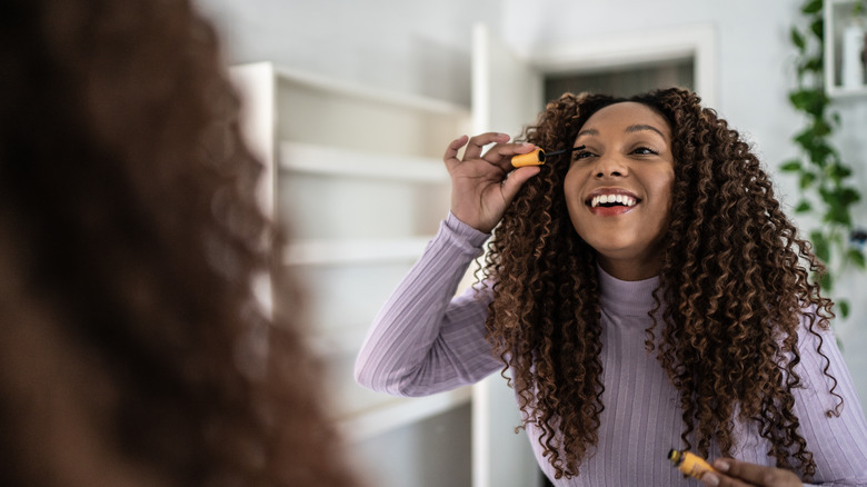 woman applying mascara in mirror