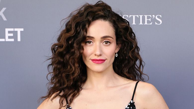 Emmy Rossum smiling with curly hair and magenta lipstick in 2026