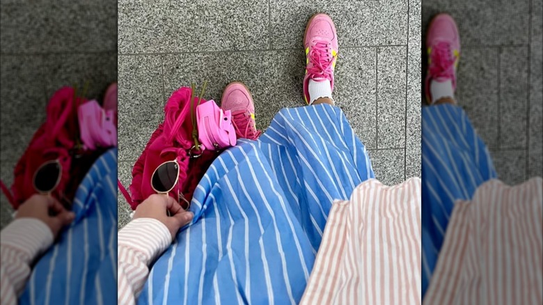 A close up of pink Adidas shoes with a blue and white skirt
