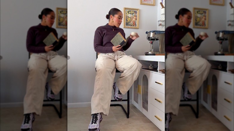 A woman wearing HOKA sneakers with white cargo pants and a brown sweater