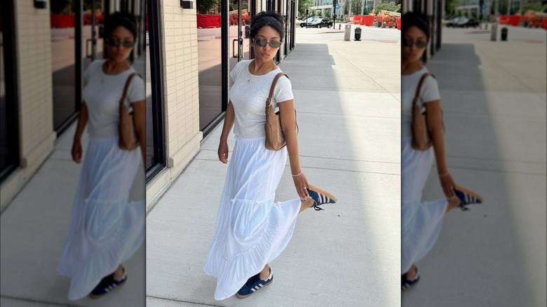 A woman in a white skirt and shirt with blue Adidas sneakers