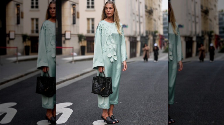 A woman in a teal green kaftan with black mules