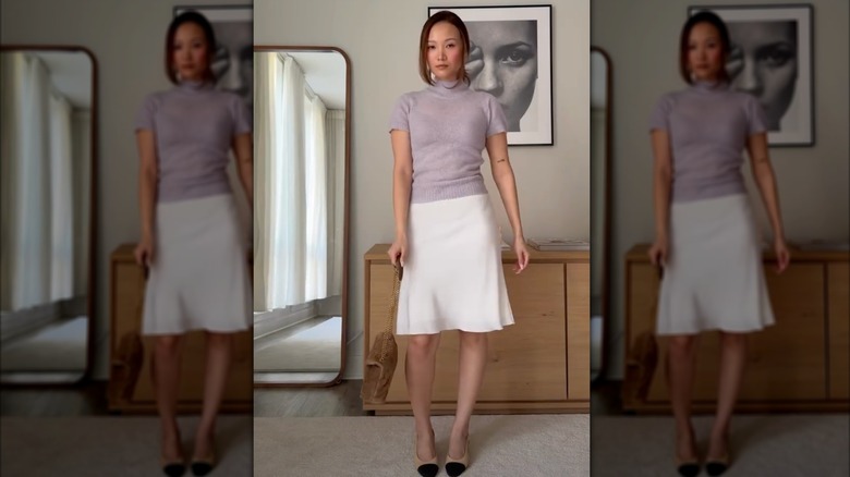 A woman in a cream skirt with a purple shirt and heels