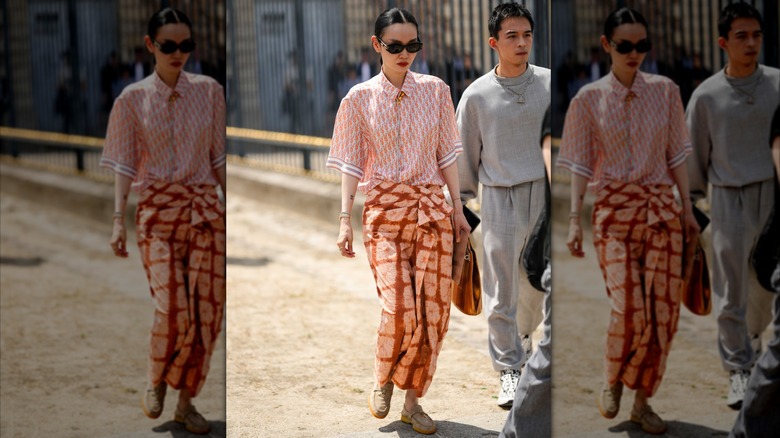 A woman wearing a brown and orange wrap skirt with an orange print top