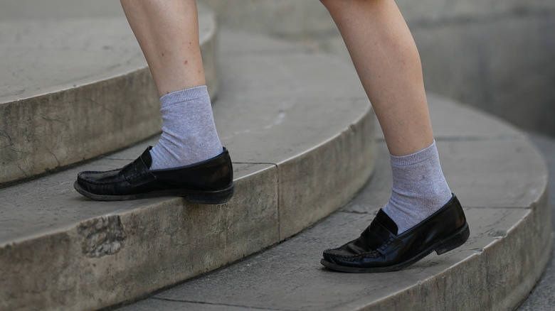 Person climbing stairs in black leather slip-on loafers and gray ankle socks