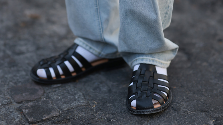 Person wearing fisherman sandals with socks and jeans