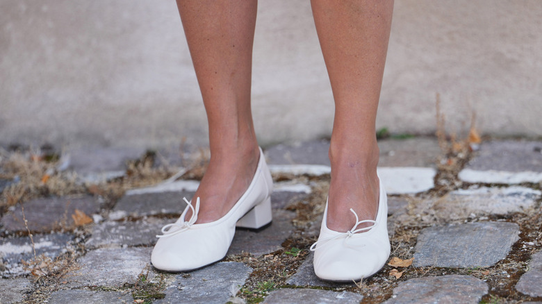 Woman wearing white low heels with thin bows