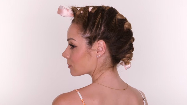 A woman on YouTube doing a heatless hair curl technique for side sleepers