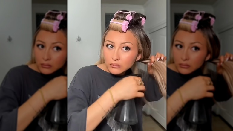 A woman putting in sponge rollers down the center of her head