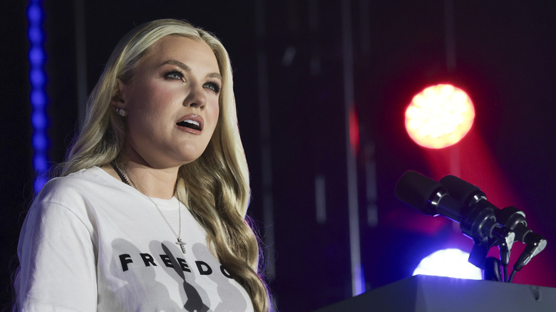 Erika Kirk in a white Freedom shirt speaking on stage