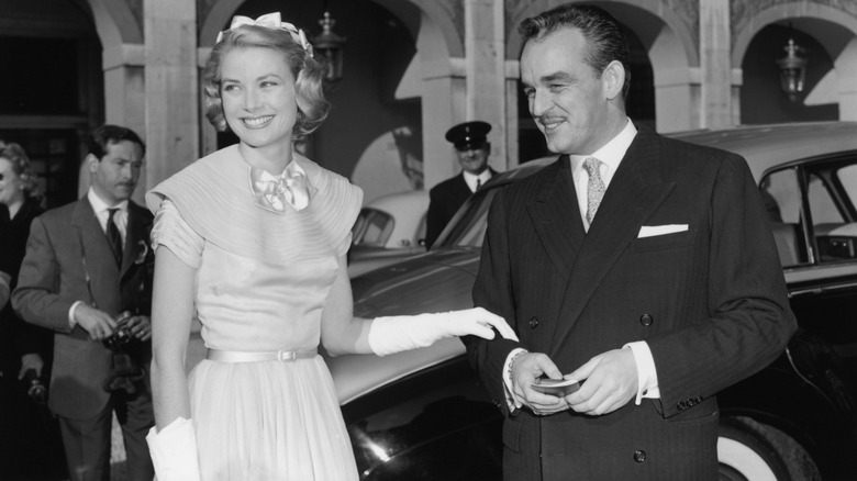 Grace Kelly with her hand on the arm of Prince Rainier III in front of car