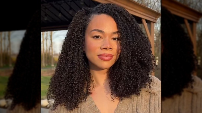 A woman with curly hair in a deep side part